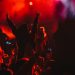 Large group of people in a concert crowd enjoying live performance on a music festival at night. Audience raising hands up.